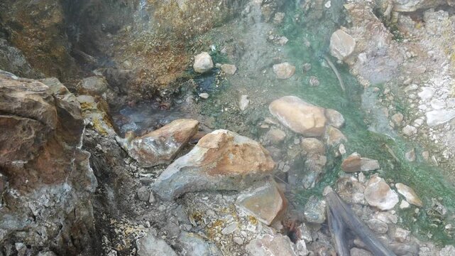 Geothermal springs in Tuscany, Italy, with mineral-rich rocks, steaming ground, and vivid green thermal deposits, showcasing volcanic activity, natural energy, and unusual landscape formations