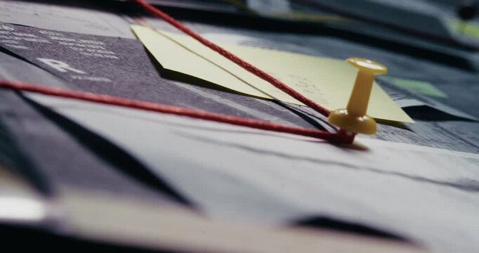 Side-angle pan reveals a crime evidence board with red string linking evidence in low light, evoking detective investigation and clandestine mystery.