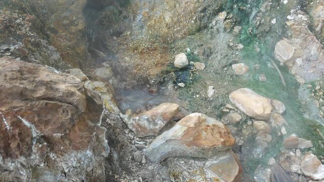 Geothermal springs in Tuscany, Italy, with mineral-rich rocks, steaming ground, and vivid green thermal deposits, showcasing volcanic activity, natural energy, and unusual landscape formations