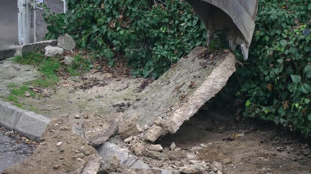A large hole in the ground with a shovel in it. The shovel is being used to dig into the ground