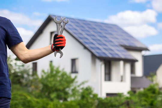 Solar Panel Technician Installing Photovoltaic Panels on Residential House Rooftop. Solar Installer Hand with Tools on Solar Panel Roof.