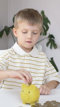 Boy in striped shirt places coin into yellow piggy bank beside scattered loose coins over time. Credit union family finance imagery shows consistent contribution to personal savings