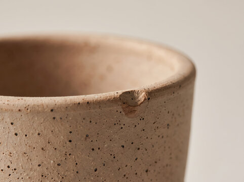 Macro shot of a chipped rim on a handmade speckled terracotta clay cup