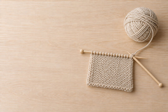 Knitting needles and beige yarn with copy space on a wooden table