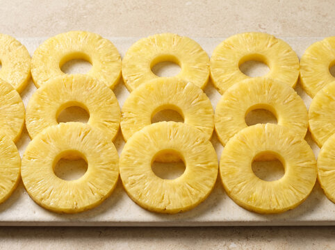 Rows of fresh sliced pineapple rings arranged on a flat surface