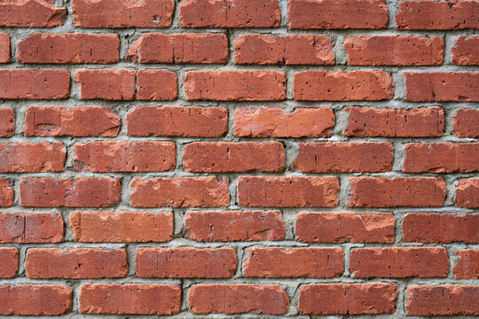 Red brick wall texture background with uneven brick edges and grey mortar joints