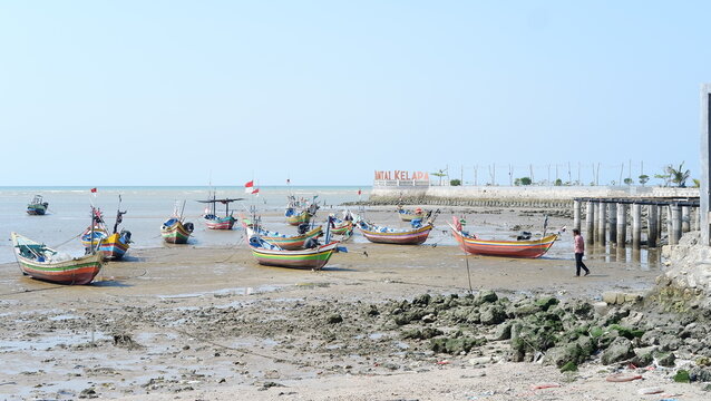 Traditional wooden fishing boats anchored on a sandy beach during a bright sunny day