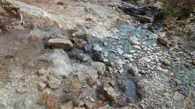 Geothermal springs in Tuscany, Italy, with mineral-rich rocks, steaming ground, and vivid green thermal deposits, showcasing volcanic activity, natural energy, and unusual landscape formations