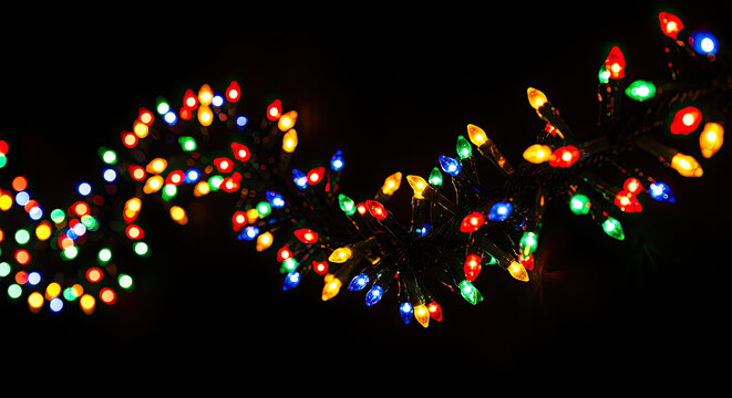 A string of colorful Christmas lights illuminates the darkness. The lights are arranged in a curved line, emitting a warm glow.