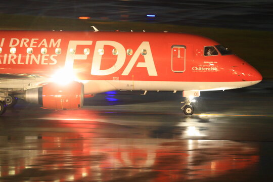 A Fuji Dream Airlines Embraer 170 in red livery is panned on the wet night apron on September 30, 2015 in Japan.