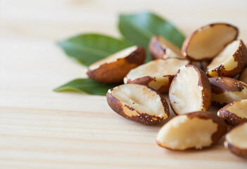 Obraz premium Healthy nutrition and superfood, organic brazil nuts with green leaves on a wooden table for vegan diet and natural plant based protein source snacks
