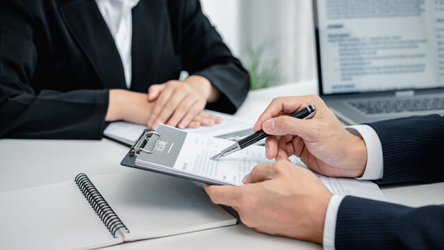 Man employer holding pen to pointing on resume and asking candid