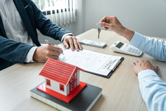 Real estate broker agent holding filing keys to the customer after signing rental lease contract of the sale purchase agreement