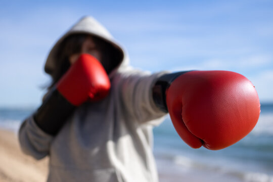 unrecognizable senior woman athlete boxing training at beach wearing red gloves