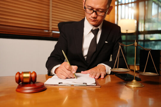 Asian Lawyer Writing on Contract Document in Legal Office Environment