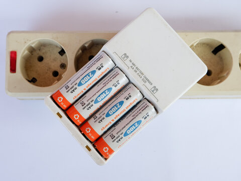 Recharging AA Batteries in Portable Charger on Electrical Power Socket Strip for Electronic Device Energy Supply