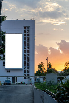 White building stands tall at sunset's glow. Sky paints orange and pink behind clouds.