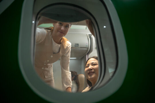Flight attendant assisting a female passenger inside an aircraft cabin, representing professional airline customer service