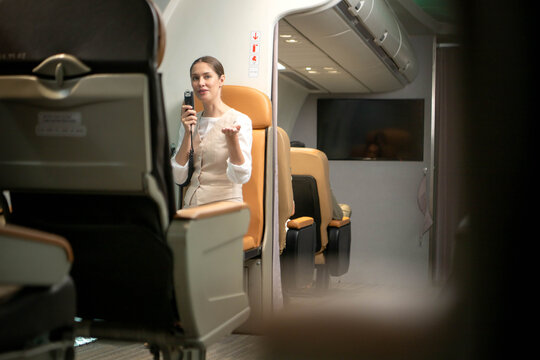 Flight attendant seated in the aircraft cabin using an intercom communication system