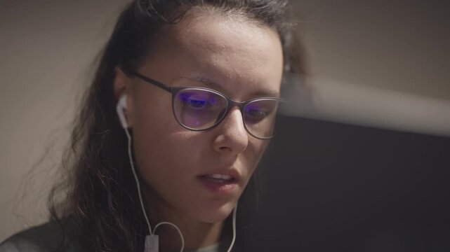 Freelancer developer woman wearing glasses is looking at a computer screen. Concept of focus and concentration as the woman stares intently at the screen with reflection in glasses
