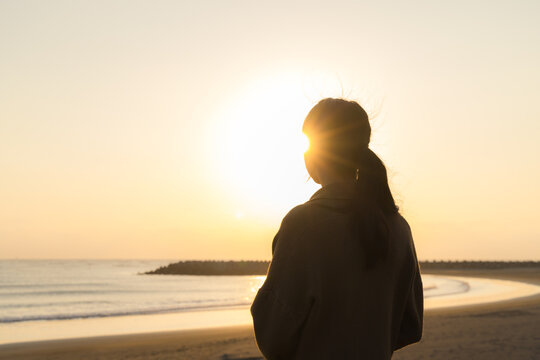 Woman watching sunset silhouette on beach