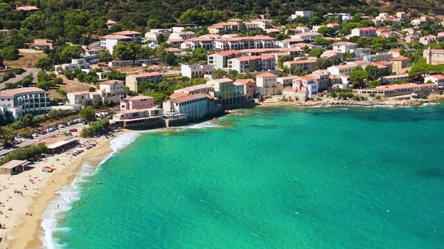 Algajola Corsica France aerial drone camera tilt down turquoise emerald sea golden sand beach waves resort town Balagne Ile Rousse region travel destination 4k video