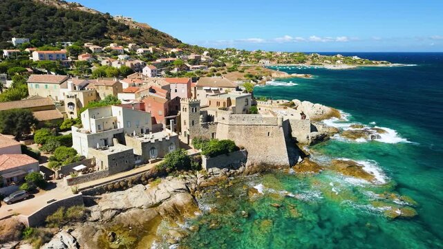 Algajola town Corsica France aerial drone flyover coastal castle fortress emerald sea orange roofs turn reveal shot rugged coast travel destination 4k footage