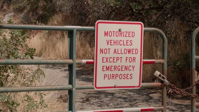 Still shot of a posted vehicle restriction sign attached to a metal trail gate.
