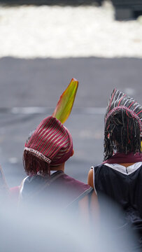 Batak people wearing traditional red ulos cloth and ornate headdress photographed closely from behind during a local Sumatran cultural ceremony