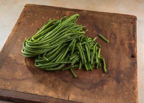 Fresh bunches of organic yardlong beans (Vigna unguiculata subsp. sesquipedalis) at a local outdoor market.