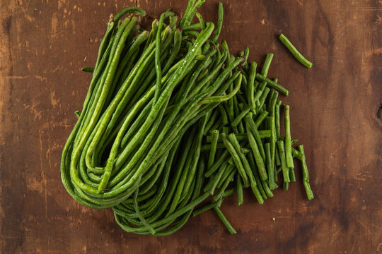 Fresh bunches of organic yardlong beans (Vigna unguiculata subsp. sesquipedalis) at a local outdoor market.