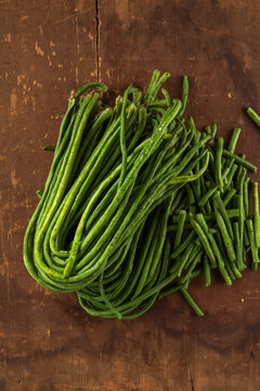 Fresh bunches of organic yardlong beans (Vigna unguiculata subsp. sesquipedalis) at a local outdoor market.