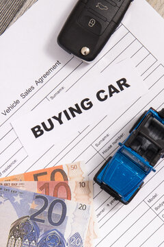 Blue toy car, key, euro banknotes and vehicle sales agreement. Inscription buying car. Sales and buying new or used car