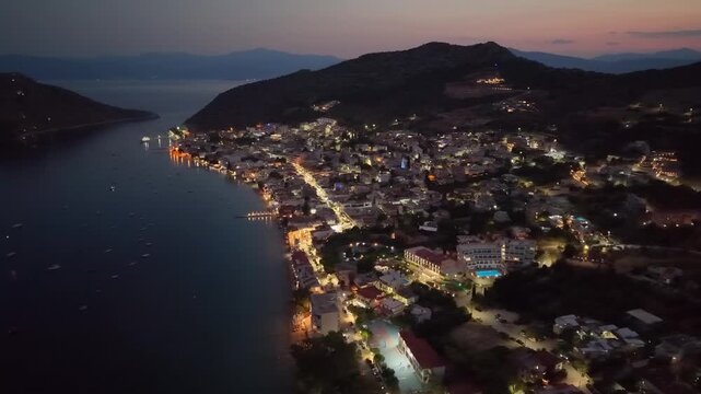 Flying over an illuminated Greek coastal town at dusk