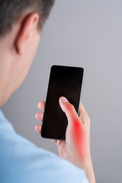 Pain in thumb with red backlight. Man using phone. Smartphone syndrome, gaming thumb and excessive screen time