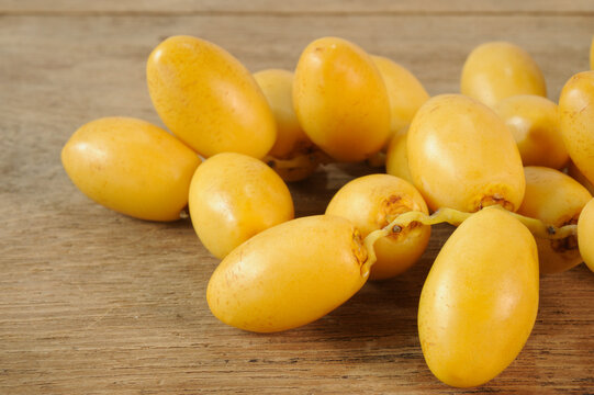Fresh yellow date palm fruit on wooden background