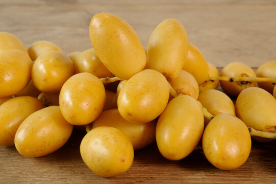 Fresh yellow date palm fruit on wooden background