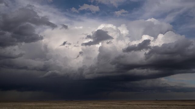 Wide angle timelapse captures dramatic storm cell clouds forming over flat USA plains, showcasing intense weather, sweeping cloud motion, and moody lighting before a severe storm.