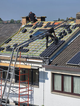 Ouvriers qui r&eacute;novent la toiture d&rsquo;une maison pour isolation et remplacement des tuiles