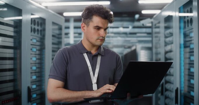 In Data Center, Focused IT Specialist Holds Laptop Inspect Server Racks and Check Network Status. System Diagnostics and Hardware Maintenance Ensure Seamless Cloud Operations. Performance Monitoring.