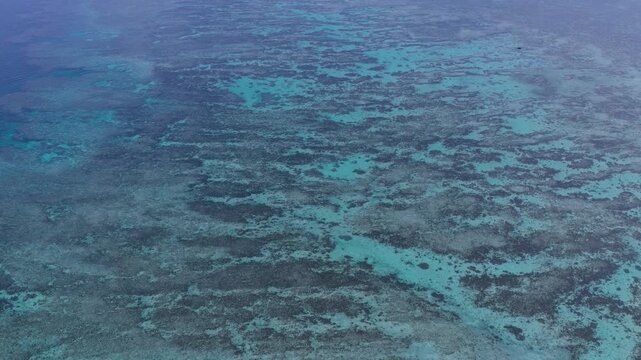 Horizontal cameo shot moving backward to the left from an elevated downward angle over the shallow coral reef waters near Kaiji Beach, Taketomi Island, Okinawa, Japan