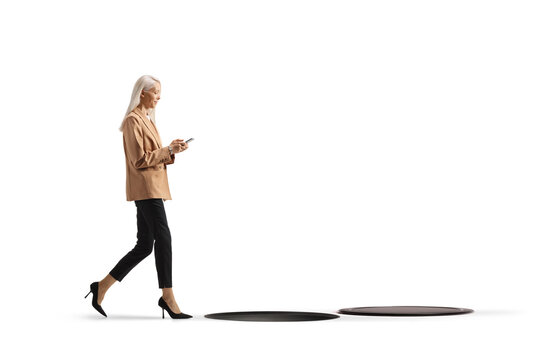 Businesswoman walking while looking at her phone towards a hole