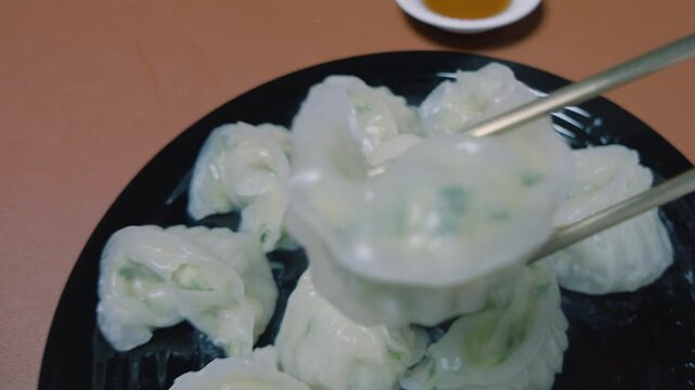 접시에 담긴 만두를 젓가락으로 들어 클로즈업해서 보여주는 모습