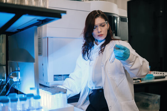 Caucasian Female Scientist Working in Lab Holding Test Tube with Safety Glasses and White Coat