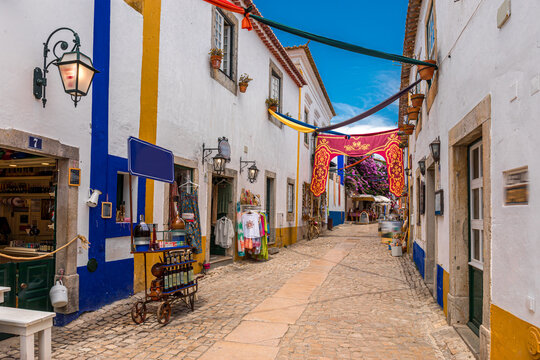 Traditional cobblestone street decorated with banners in historic Obidos, Portugal.