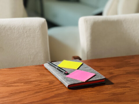 Bright indoor notebook with pen and sticky notes resting on wooden table