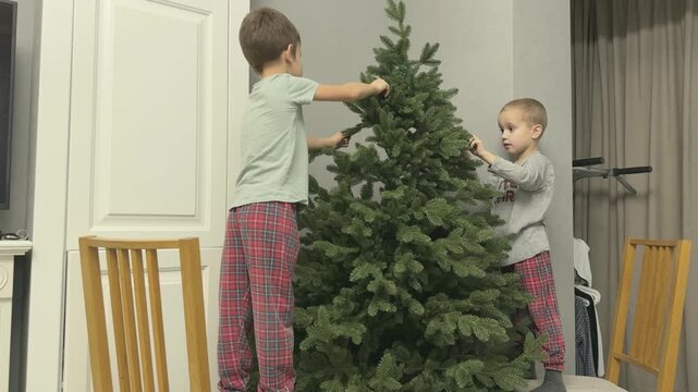 Children helping to assemble Christmas tree at home. Family teamwork before decorating. Perfect for parenting and holiday storytelling. 