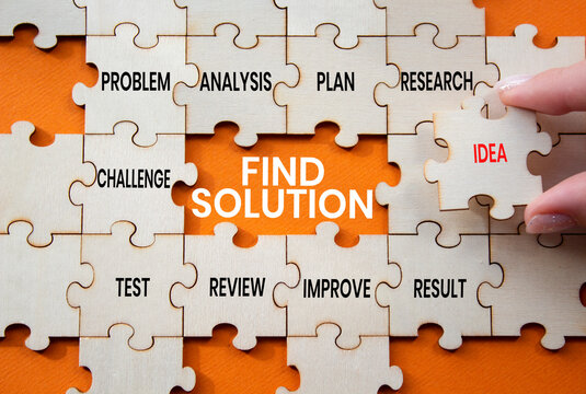 Find solution symbol. Concept words find solution on wooden puzzle pieces. Businessman hand. Beautiful orange background. Problem solving concept. Copy space.