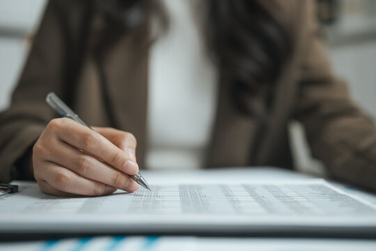Audit notes guide auditing as an auditor checks budgeting in a business background of rows, the silver pen adding audit notes for auditing as the auditor checks budgeting in this business background.