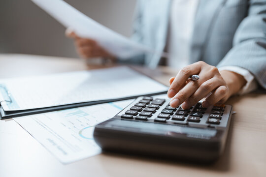 Financial checks need calculation for accounting as an accountant reads a statistic from a sheet, pressing a key for financial sums and calculation in accounting as the accountant checks a statistic.